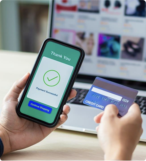 Person making an online credit card payment via mobile while shopping on a laptop – representing secure e-commerce payments.